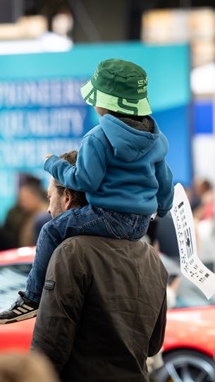 Child on his father's shoulders watching a car