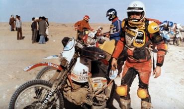 Vintage photo of Éric de Seynes in biker gear, in front of his bike and with his co-drivers at the 1982 Dakar Rally