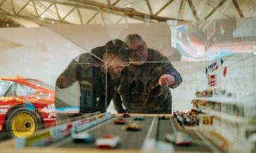 2 men look at a miniature of a motor-racing stadium