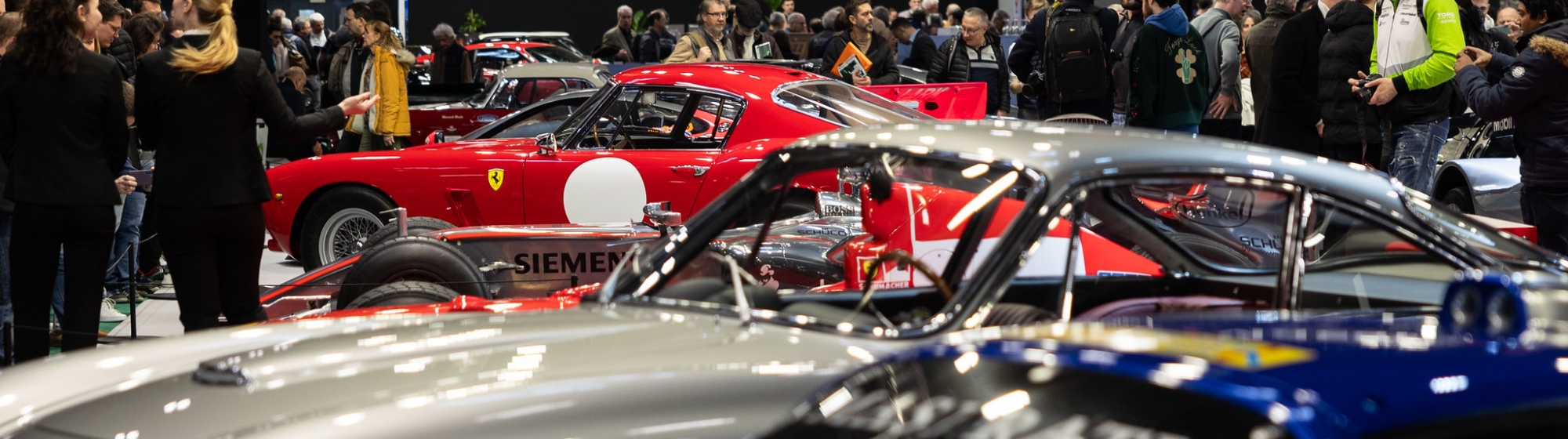 red, grey and blue classics cars with crowd in car exhibition