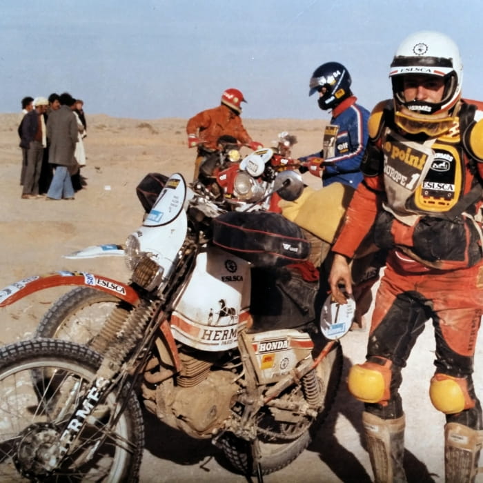 Eric de seynes debout devant sa moto, durant un DAKAR