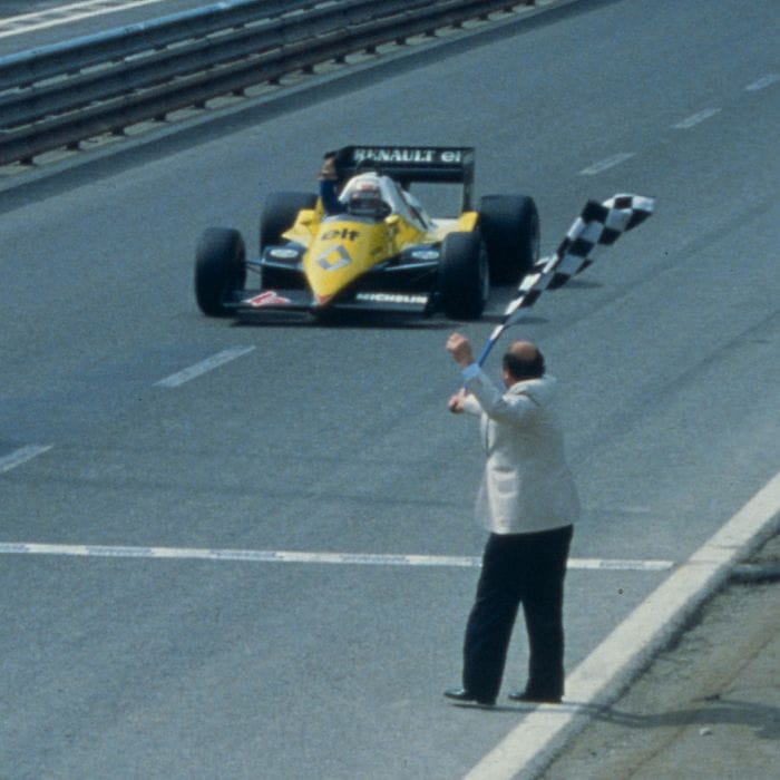 Voiture renault jaune de F1 à l'arrivé d'une course avec un homme drapeau