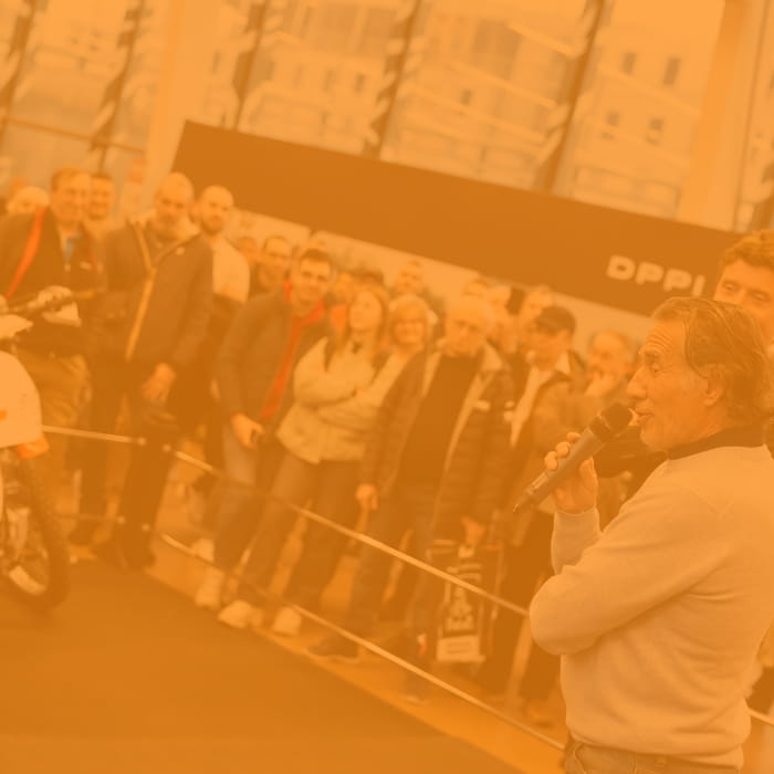 Man with a mic presenting a motorcycle in exhibition with crowd