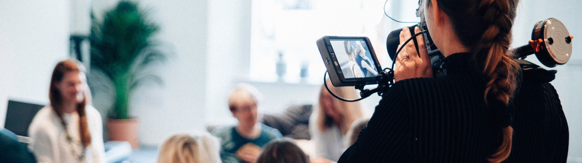 un groupe de personnes discutant et une femme avec une caméra vidéo les filmes